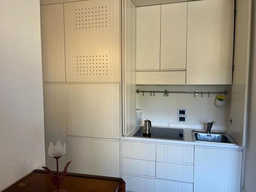 a kitchen with white cabinets and a sink and a table at Villa Maria Callas Sirmione in Sirmione
