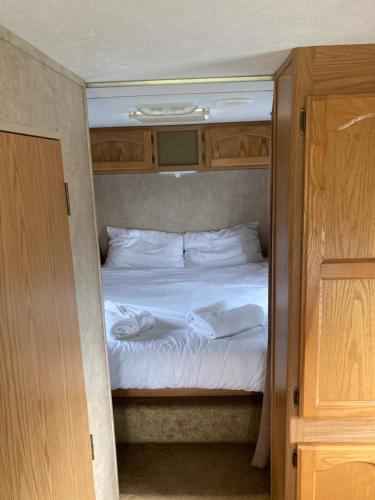 a bedroom with a bed with white sheets and pillows at 5th Wheel Trailer in Bere Alston