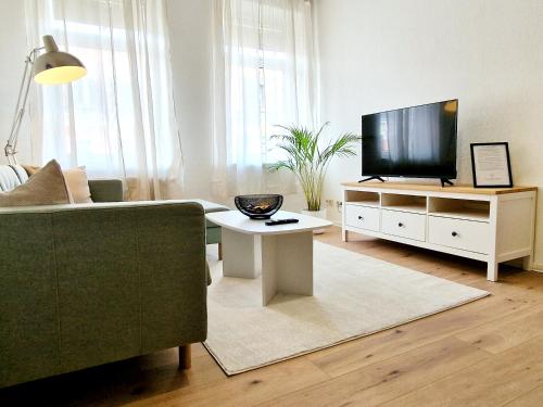 ein Wohnzimmer mit einem Sofa und einem Flachbild-TV in der Unterkunft HappySide - Sm00th - Landhaustil - WLAN - Nespresso in Leipzig