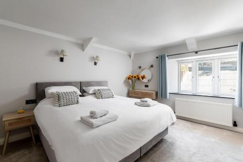sypialnia z dużym białym łóżkiem z ręcznikami w obiekcie The Sail House w mieście Brixham