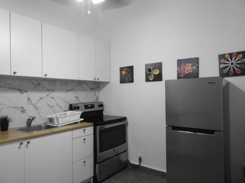 a kitchen with a black refrigerator and white cabinets at Casa Del Sol-Unit A in Bayamon