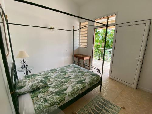 a bedroom with a canopy bed and a sliding glass door at Chambre indépendante vue mer et montagne in Vieux-Habitants