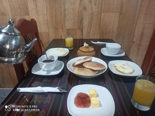 a table topped with plates of food and orange juice at Casa D´Maria in Ollantaytambo