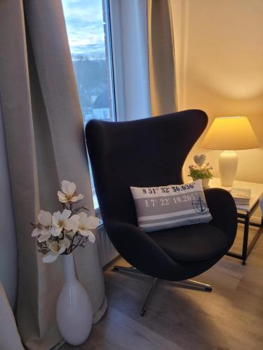 a black chair and a vase with flowers in a room at Heimathafen Hohwacht in Hohwacht
