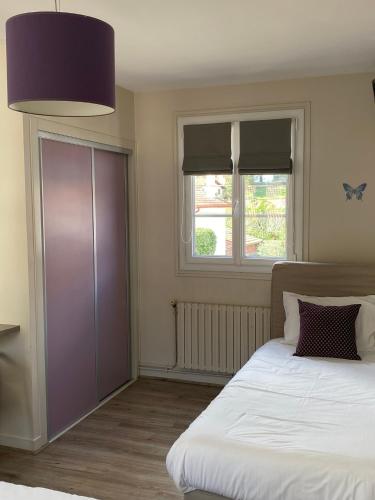 a bedroom with a bed and a purple cabinet and two windows at Hôtel Juantorena in Saint-Étienne-de-Baïgorry