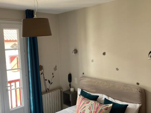 a bedroom with a bed with a blue curtain and a window at Hôtel Juantorena in Saint-Étienne-de-Baïgorry