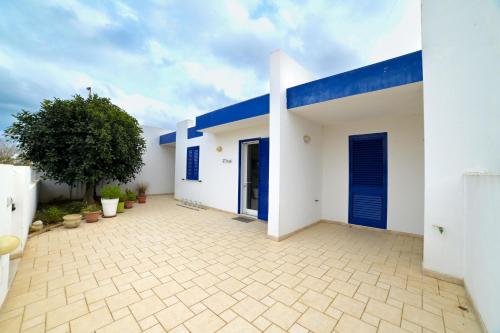 una casa bianca con tetto blu e cortile di Villetta da Leo a Torre dell'Orso