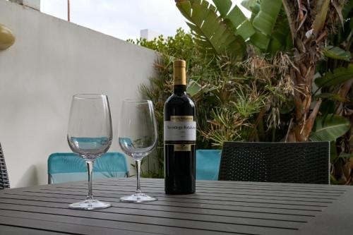 una bottiglia di vino seduta su un tavolo con due bicchieri da vino di Villetta da Leo a Torre dell'Orso