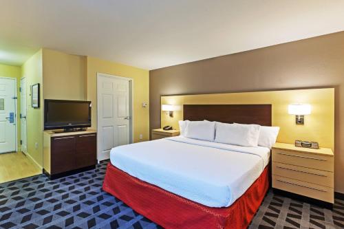 ブロークン・アローにあるTownePlace Suites by Marriott Tulsa Broken Arrowの大型ベッド1台、薄型テレビが備わるホテルルームです。