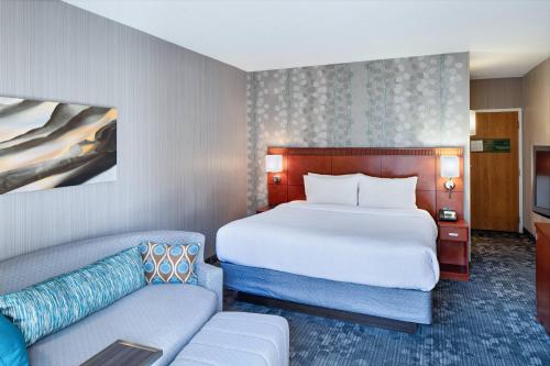 a hotel room with a bed and a couch at Courtyard Cincinnati Blue Ash in Blue Ash