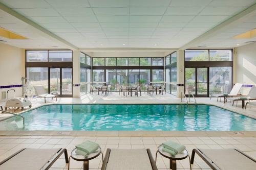 a large pool with chairs and tables in a building at Courtyard Cincinnati Blue Ash in Blue Ash