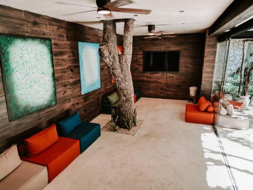 a living room with a tree and red and blue couches at Kaaba Luum Jungle Villas in Chemuyil