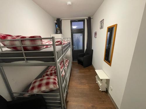 a room with three bunk beds and a chair at Restaurant Hostel Aan Tafel in Lunteren