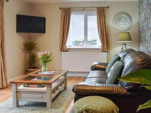 a living room with a leather couch and a coffee table at Cremlyn Lodge in Beaumaris
