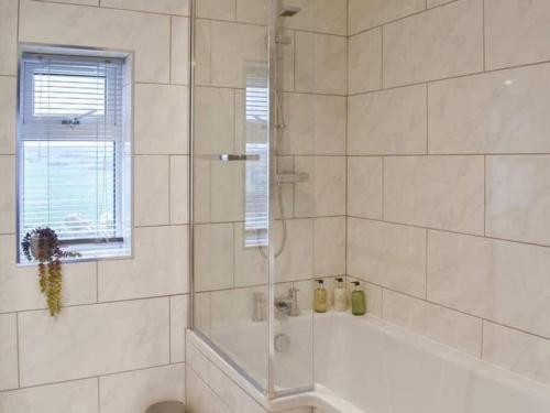 uma casa de banho branca com uma banheira e um chuveiro em Cremlyn Lodge em Beaumaris