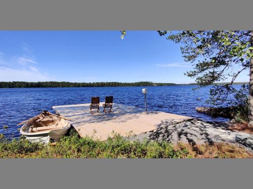 zwei Stühle und ein Boot auf einem Dock auf einem See in der Unterkunft Holiday Home Kiviniemi by Interhome in Siikakämä