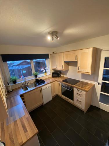 a kitchen with wooden cabinets and a sink and a window at Delightful, central 3 bedroom house with garden. in Inverness