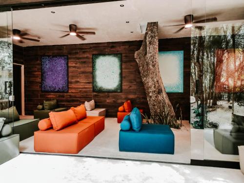 a living room with orange and blue furniture and a tree at Kaaba Luum Jungle Villas in Chemuyil