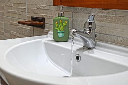 a bathroom sink with a green soap bottle on it at Ficu Pala Holiday Home in Noto