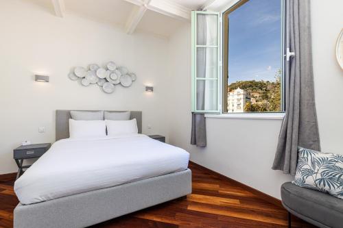 a bedroom with a bed and a window at Le Palais de Menton - Elegant apartment with sea view in Menton