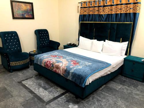 a bedroom with a bed and two chairs at Hotel Air inn in Lahore