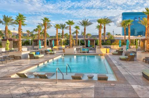 a hotel pool with palm trees and tables and chairs at Balcony Full Strip View Suite MGM Signature FREE VALET in Las Vegas