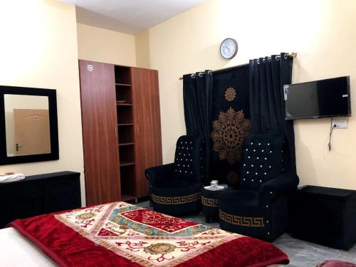 a bedroom with a bed and two chairs and a tv at Hotel Air inn in Lahore
