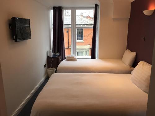 two beds in a room with a window at Hill View Hotel in Blackburn