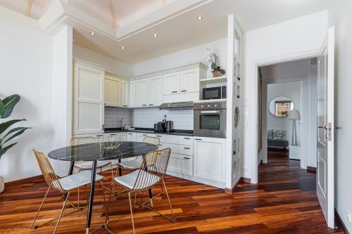 une cuisine avec des armoires blanches et une table et des chaises dans l'établissement PALAIS DE MENTON - Elegant apartment with sea view, à Menton