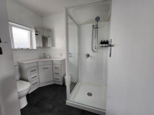 a white bathroom with a shower and a toilet at Art Deco Beauty on The Bay Hill in Timaru