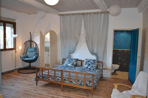 un salon avec un lit et une chaise dans l'établissement Cocoon Gîtes 2-4 ou 6 pers avec jacuzzi entre Anduze et Alès, à Carnoulès