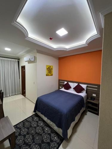 a bedroom with a bed and an orange wall at Hotel del Parque in Ciudad del Este