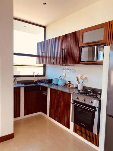 a kitchen with wooden cabinets and a stove top oven at Villa Luasah in Vila Praia Do Bilene