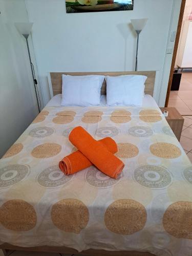 Una cama con dos almohadas naranjas. en Maison d'une chambre avec piscine partagee terrasse amenagee et wifi a Petit Bourg, en Petit-Bourg