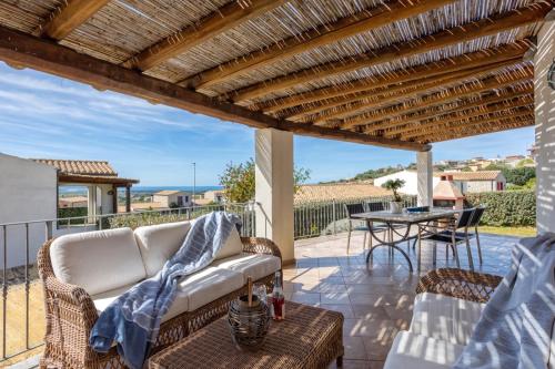 eine Terrasse mit einem weißen Sofa und einem Tisch in der Unterkunft The Veranda Holiday in Badesi