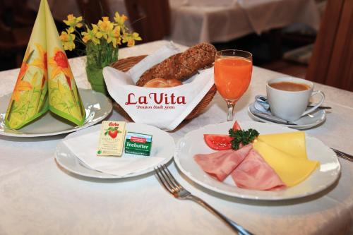 a table with plates of food and a cup of orange juice at Pension Stadt Grein in Grein