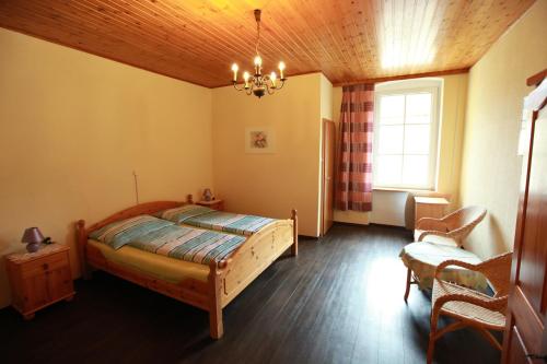 a bedroom with a bed and a chair and a window at Pension Stadt Grein in Grein