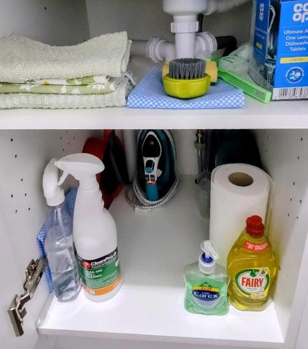 a shelf with cleaning products and a sink at Self catering upper floor flat at Woodend house in Balmacara