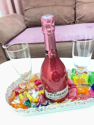 リュブリャナにあるMURIC Apartman 2のボトル1本とお菓子付きテーブルの上にグラス2杯