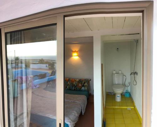 a room with a toilet and a sliding glass door at Surf HouseMaroc in Essaouira