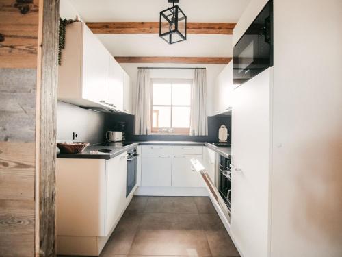 uma cozinha com armários brancos e uma janela em Holiday Home Waldkauz-5 by Interhome em Pfarrwerfen