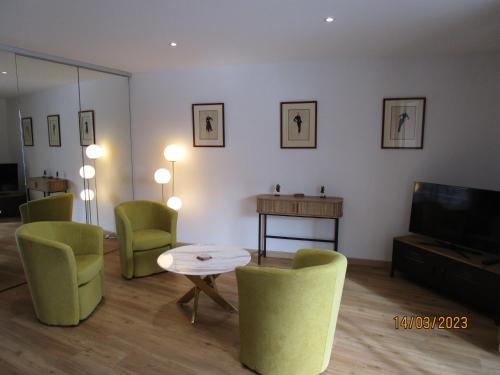 een woonkamer met groene stoelen, een tafel en een televisie bij Très belle vue Canal du Midi in Béziers
