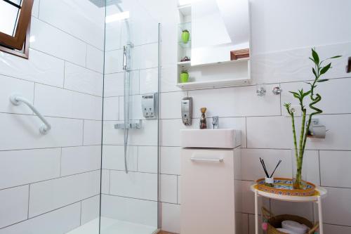 baño blanco con ducha y lavamanos en Geko Hotels, en Los Llanillos