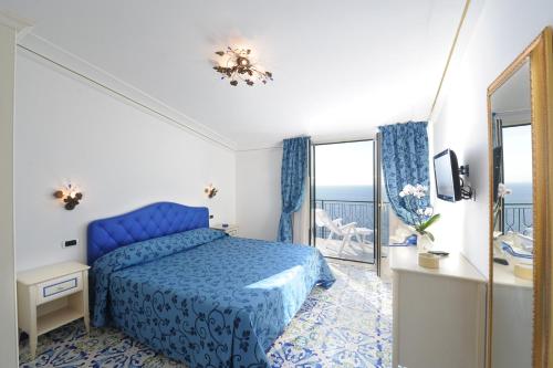 a bedroom with a blue bed and a balcony at Alba di Praiano in Praiano