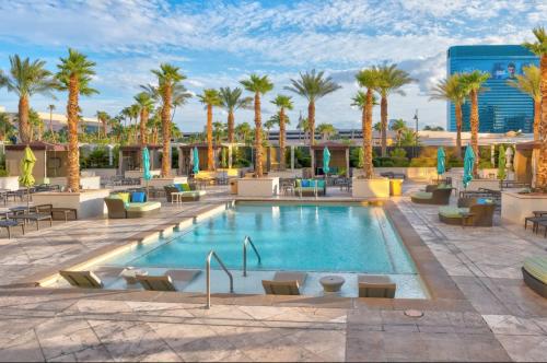 una piscina de hotel con palmeras, mesas y sillas en Stunning Balcony Strip View MGM Signature * Free Valet, en Las Vegas