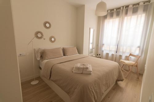 a white bedroom with a bed with a towel on it at LA TERRAZA DE LA VEGA - Ubicación inmejorable , wifi , terraza y parking gratuito in Oviedo