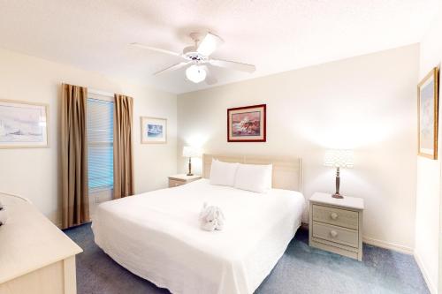 1 dormitorio con cama blanca y ventilador de techo en Islander E 2007, en Fort Walton Beach