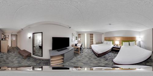 a hotel room with two beds and a flat screen tv at Wingate by Wyndham Lincoln Airport East I-80 in Lincoln