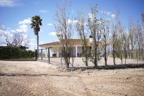 una casa con una valla y árboles delante de ella en La Casilla, en Deltebre