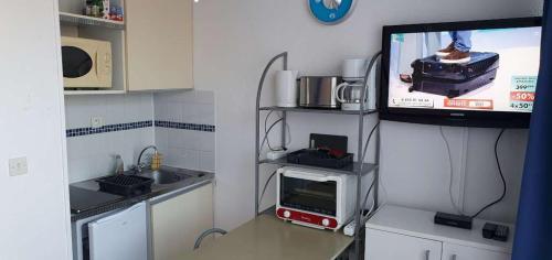 Il comprend une petite cuisine avec une télévision et une cuisine avec une fenêtre. dans l'établissement Gruissan studio aux Amarines au bord de la plage du Grazel, à Gruissan